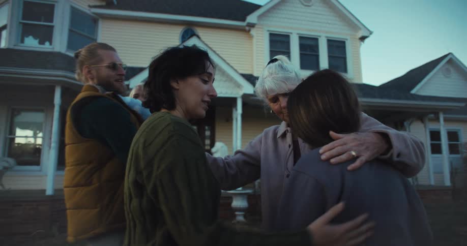 A family greet and hug in front of the home