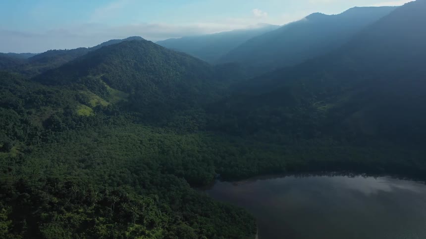 A wide aerial view of lush green mountains with lake