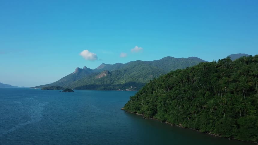 The ocean meets a coastal area that is lined with mountains covered in vegetation