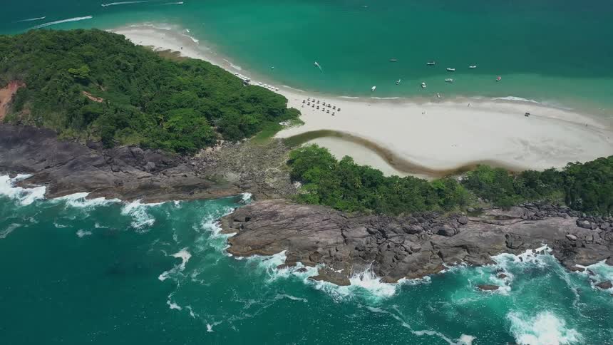 Aerial view of a tropical beach with turquoise waters and rocky coastline