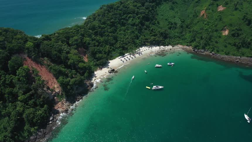 Aerial view of a tropical coastline with lush hills and turquoise water