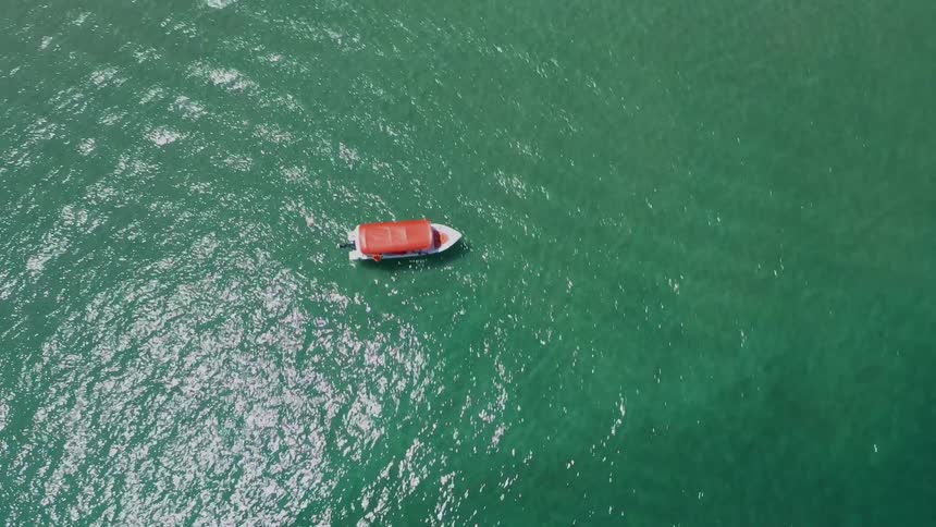 The boat is near the shore of the small island