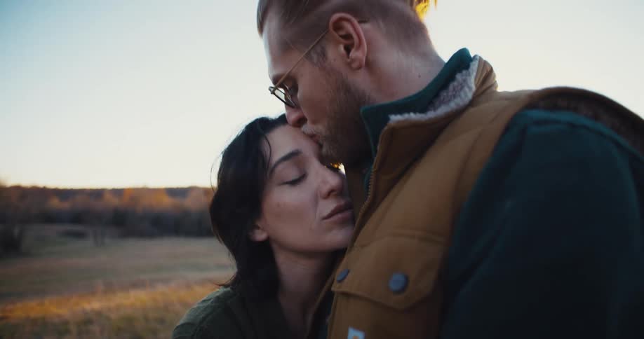 Man kisses a womans forehead while they embrace outdoors