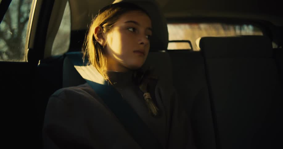 Girl sitting in the back seat of the car looks thoughtfully out the window