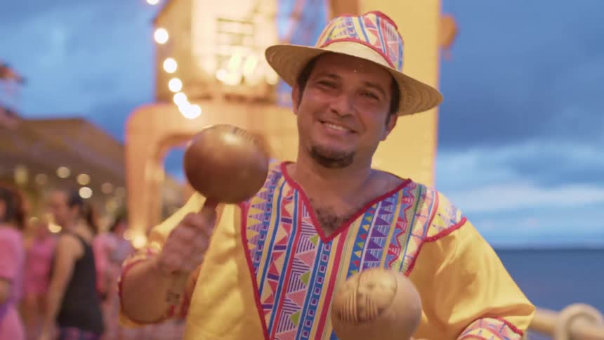 The man is playing the maracas by the shore