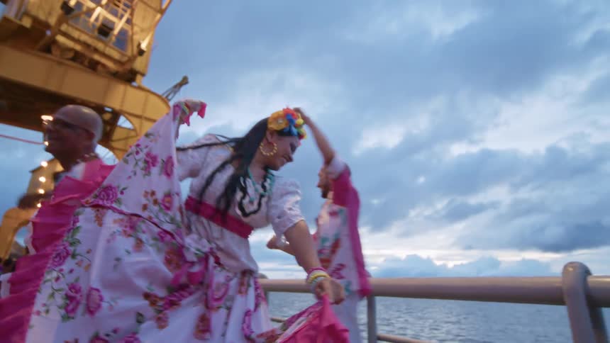Dancers in colorful costumes celebrating at an illuminated port area