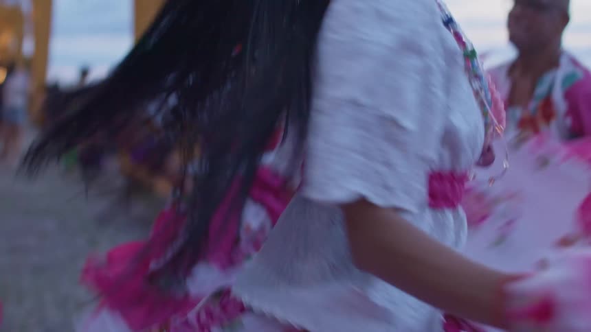Smiling woman dances with colorful accessories and flowers on her head