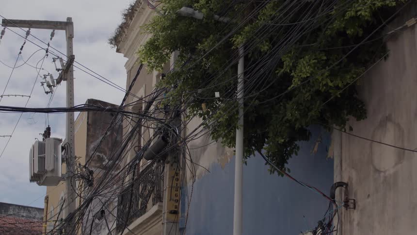 Utility poles on an old street with a mess of cables passing next to old buildings