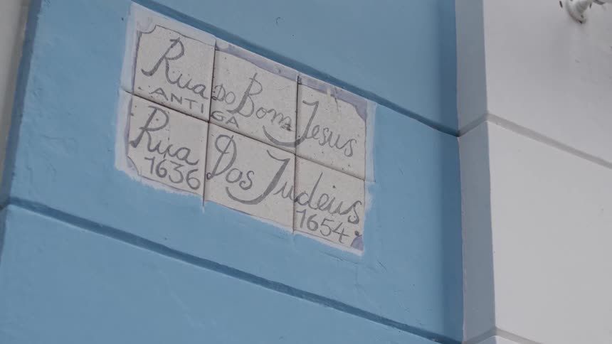 Text written on a tile on the outside of a blue wall