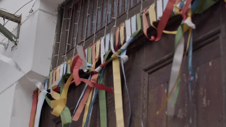 Streamers of many colors hang above a large wooden and damaged door