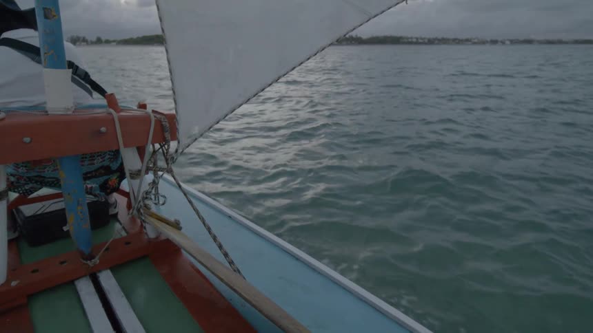 Person sailing a small boat with a sail on calm waters