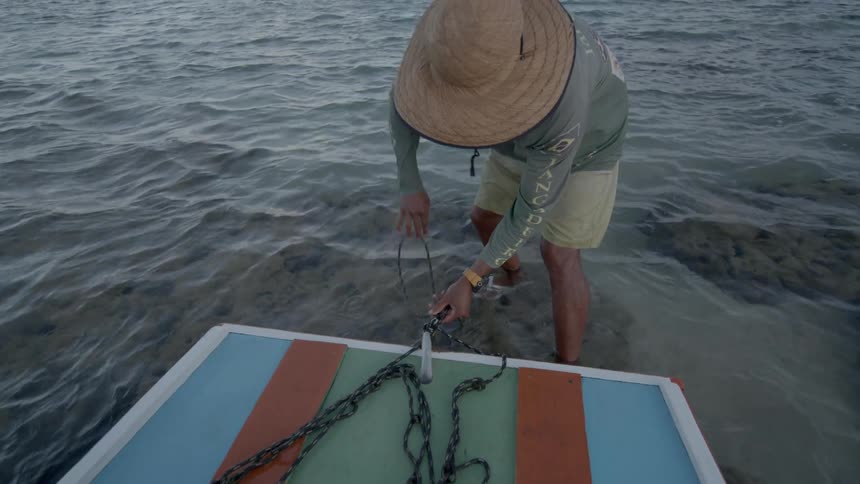 The man is tying up his small boat on the shore