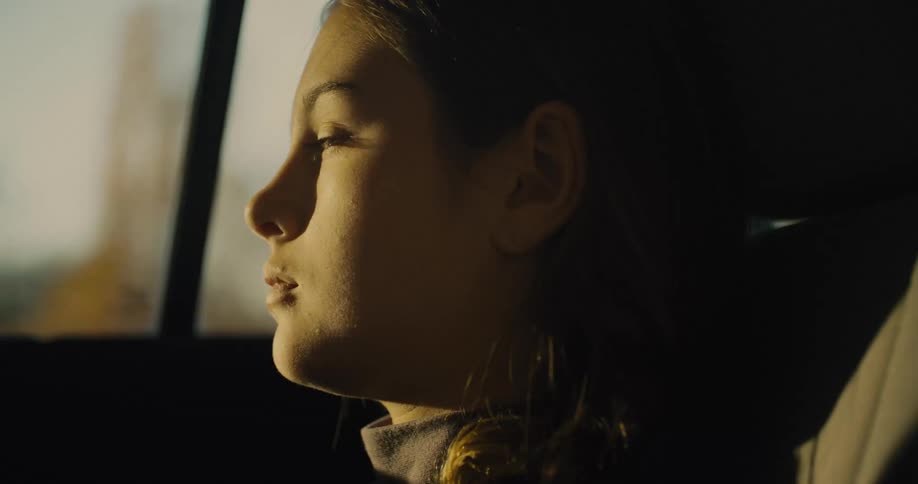 The girl is looking out the window while riding in the car