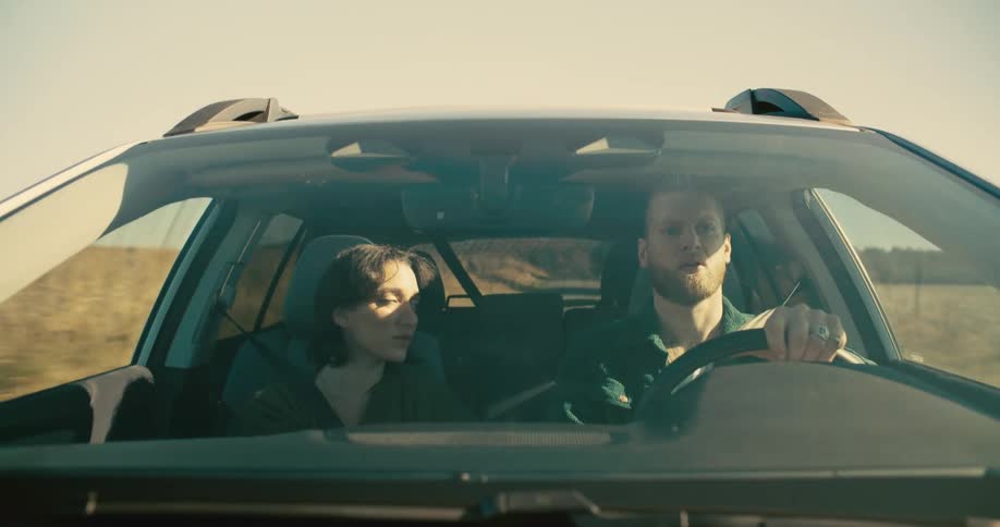 A man drives silent and angry while a woman continuously stares at him