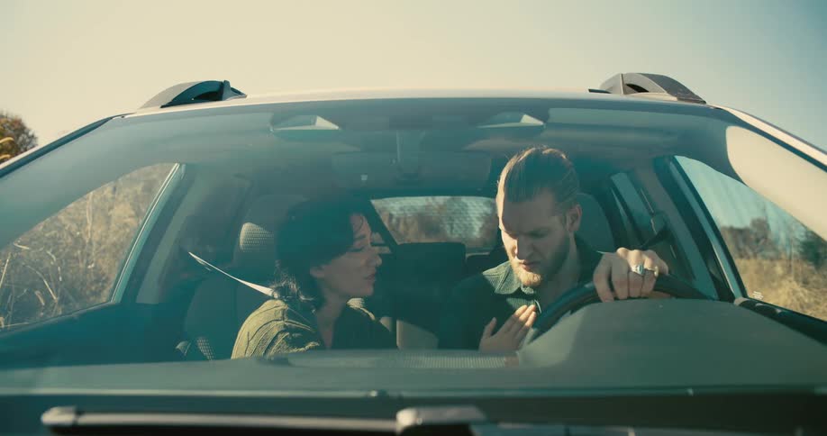 A wife consoles emotionally broken husband inside a parked car