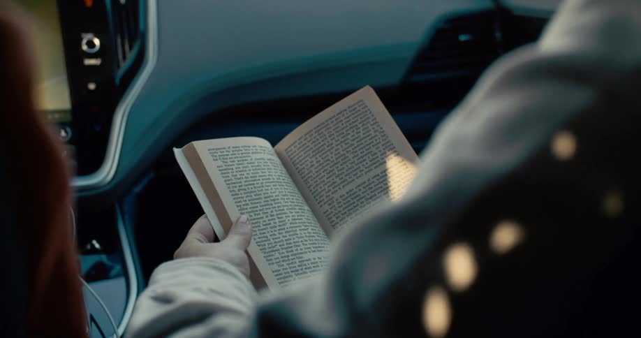 The passenger in the car is reading a book