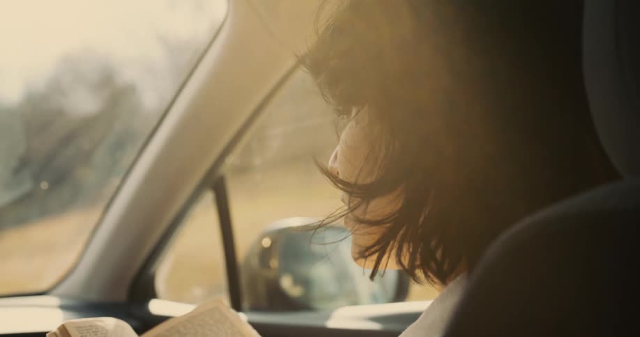 Female reading a book in a car during a road trip