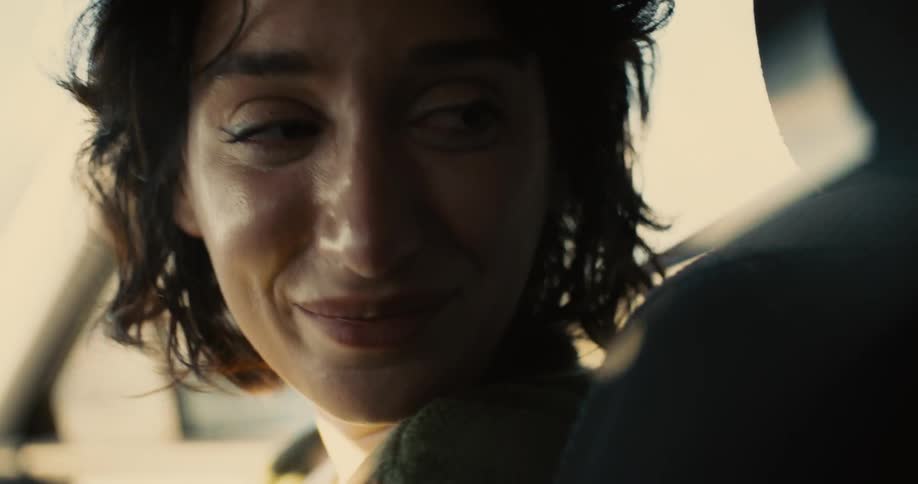 A woman in the front passenger seat looks back while experiencing mixed emotions