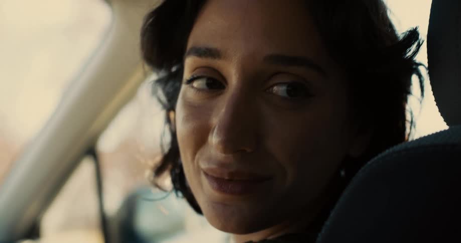 Woman sitting in a moving car looking back and talking