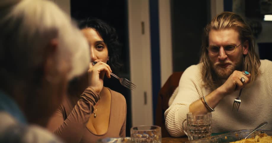 Elderly woman and family members share a meal together at the table