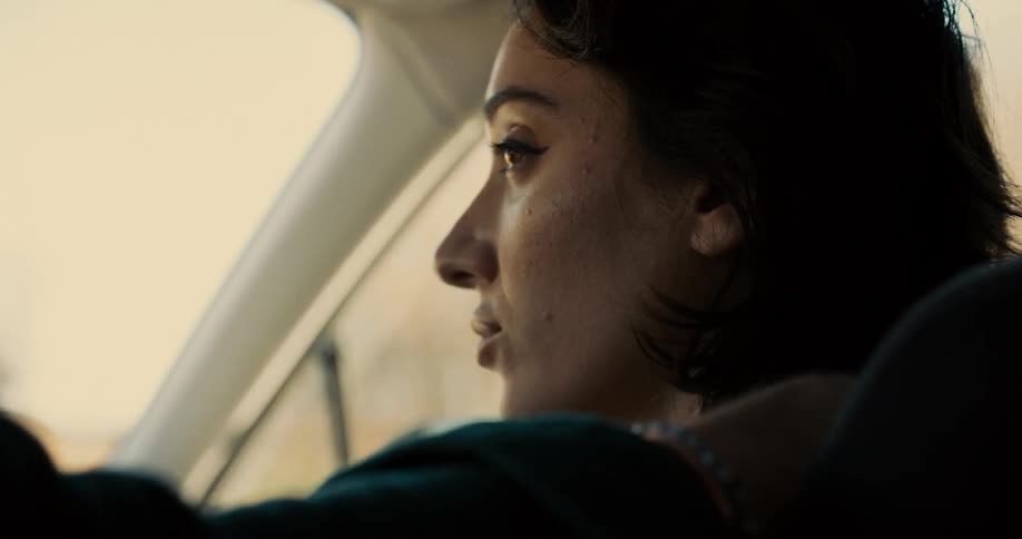 A young woman sits in the passenger seat of a car filled with sadness