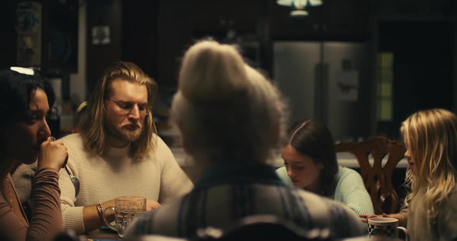 A family of five sits around a table having dinner