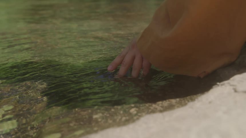 Hand gently touches the surface of clear water