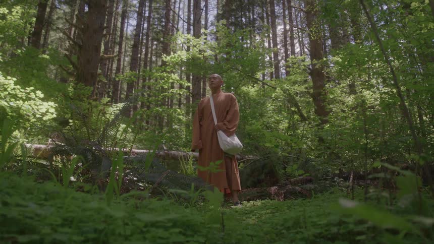 Monk with eyes closed and concentrating with a white bag in the middle of a forest