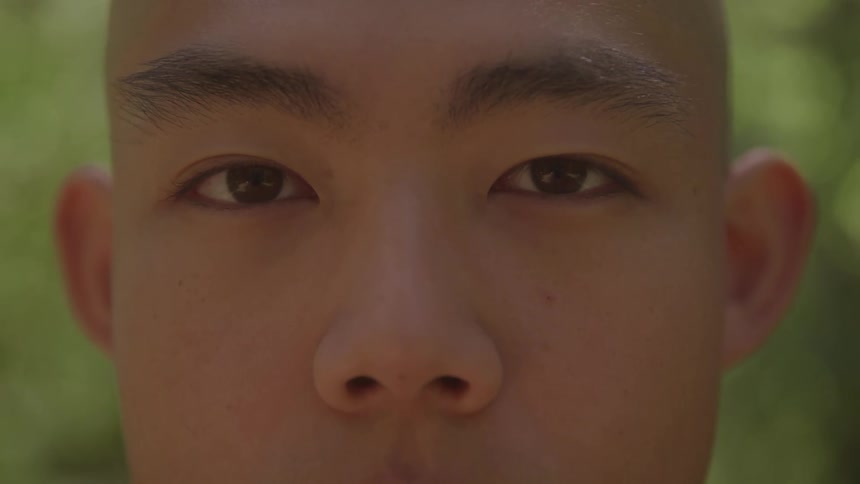The video shows a man with a shaved head and a light complexion whose eyes are initially closed he then slowly opens his eyes and stares directly at the camera with an intense unblinking gaze