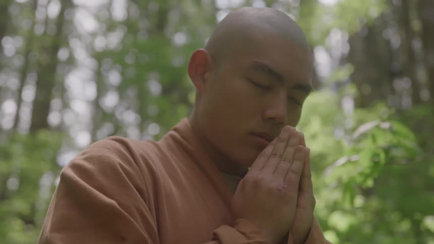 Monk meditates with eyes closed in a forest