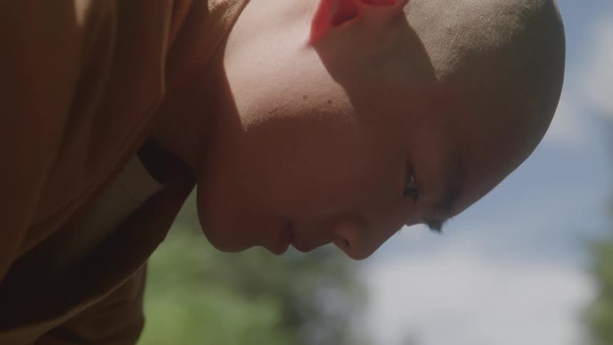 A side view of a monk looking downward outdoors
