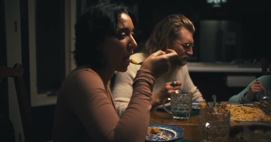 A family shares a meal together at a dimly lit dining table