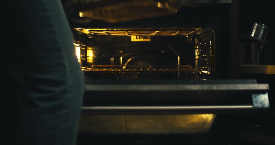 A woman removes a tray from the oven