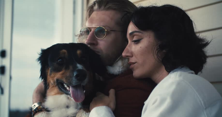 A couple hug and pet their dog