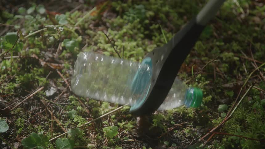 Trash picker grabber picking up a discarded plastic water bottle from the ground
