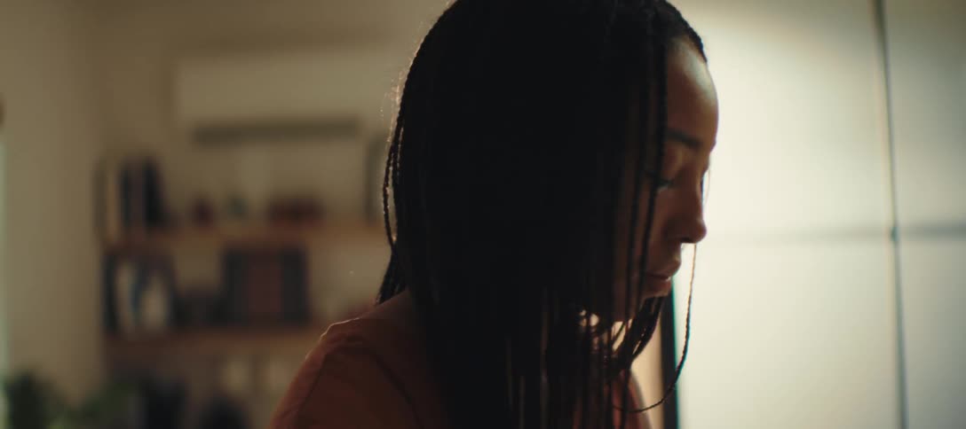 Woman with braids and a serene expression in a naturally lit room