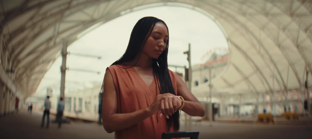 A woman standing and raising her wrist to check the time on her watch