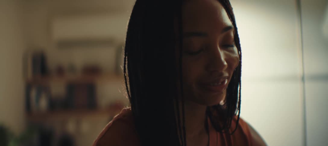 The woman is smiling while doing something at home