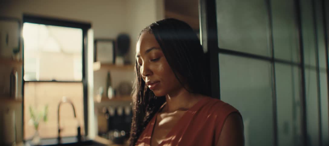 A woman standing in a kitchen looking at and using her phone