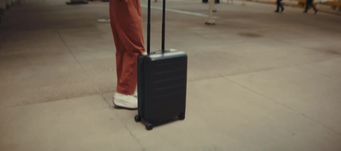 A woman pushing a baggage trolley arrives at a train station