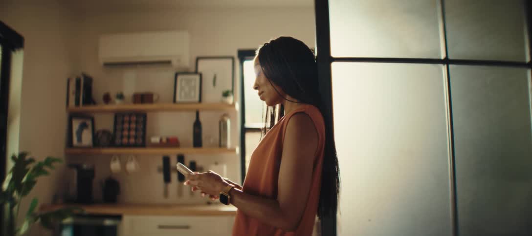 Woman texting on smartphone near kitchen indoors