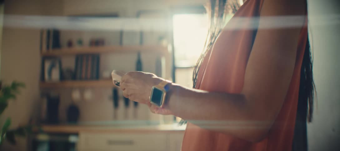 A side view of a person using a smartphone is shown the person is holding their phone in one hand and looking at their smartwatch on the other