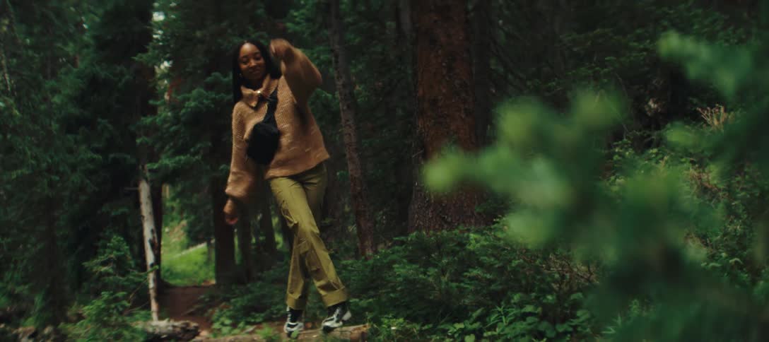 Woman walks playfully on a log in the forest