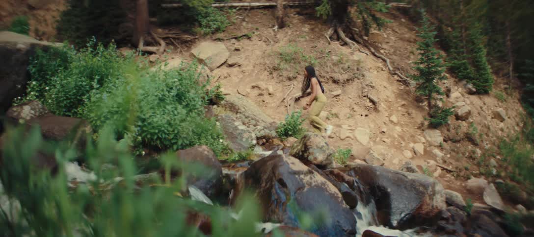 Person walking along a rocky trail beside a stream in the forest
