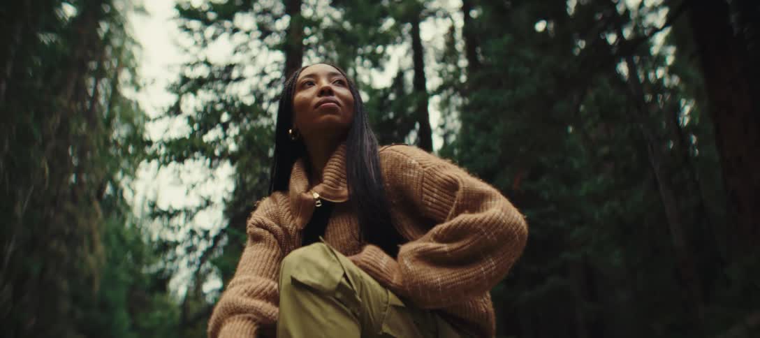 A woman seated peacefully enjoying nature in a dense forest