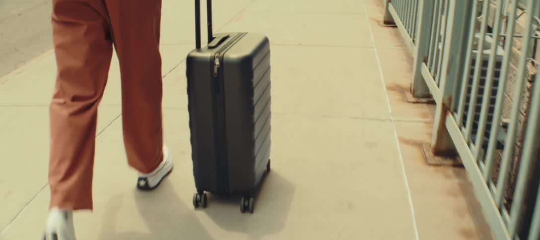 Woman walks down the sidewalk pulling a suitcase