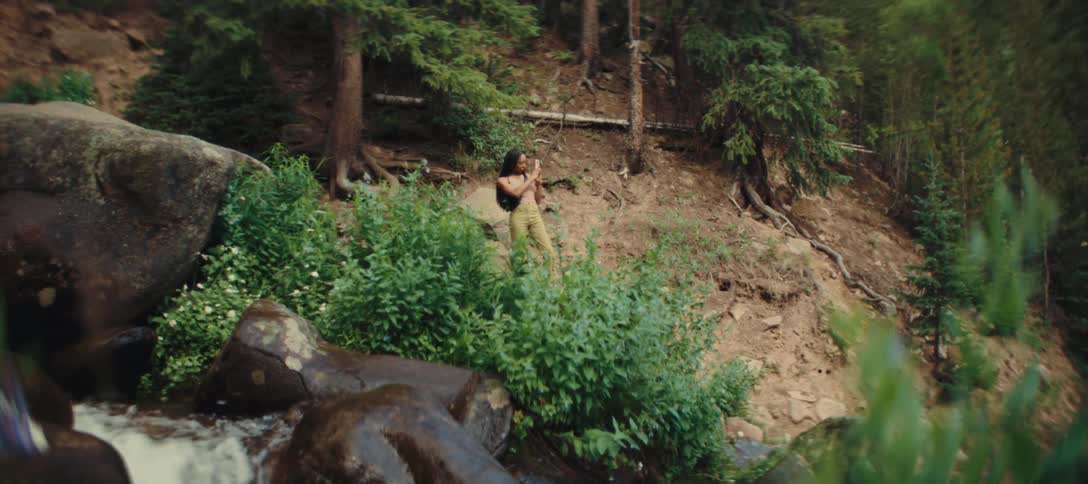 Woman taking photos near a stream in a forest area