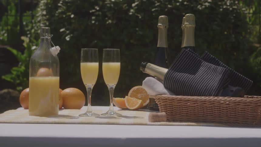 Sliced oranges two glass cups of citrus and bottles of wine on a table outdoor