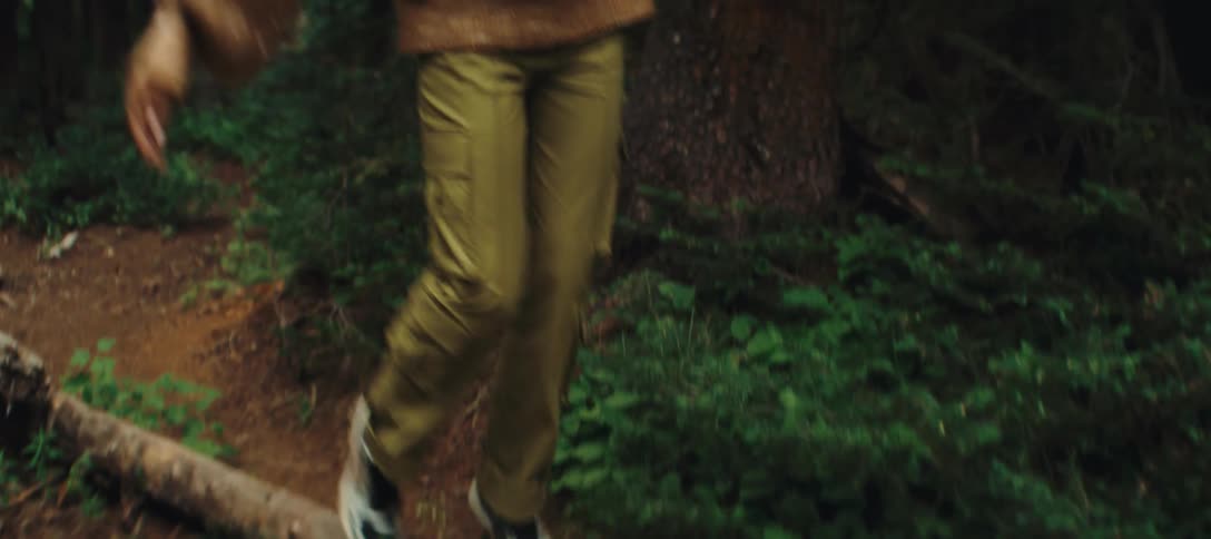 The woman balances on a log as she hikes in the forest