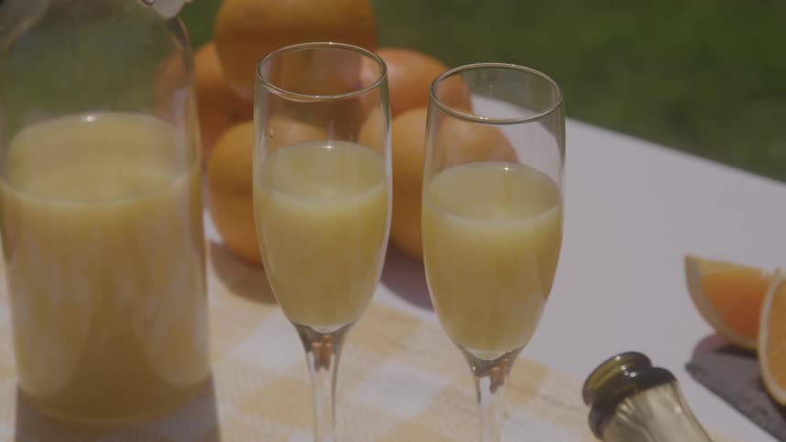 Two glasses of orange juice on a table outdoors